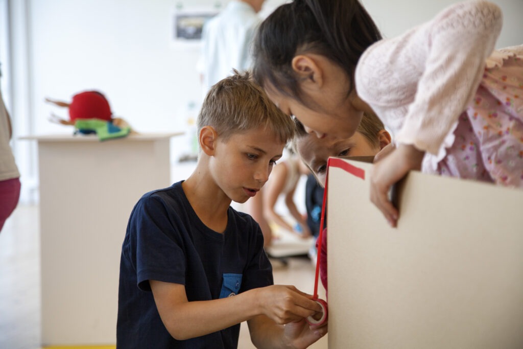Barn som samarbetar i formgivning och bygger föremål i kartong
