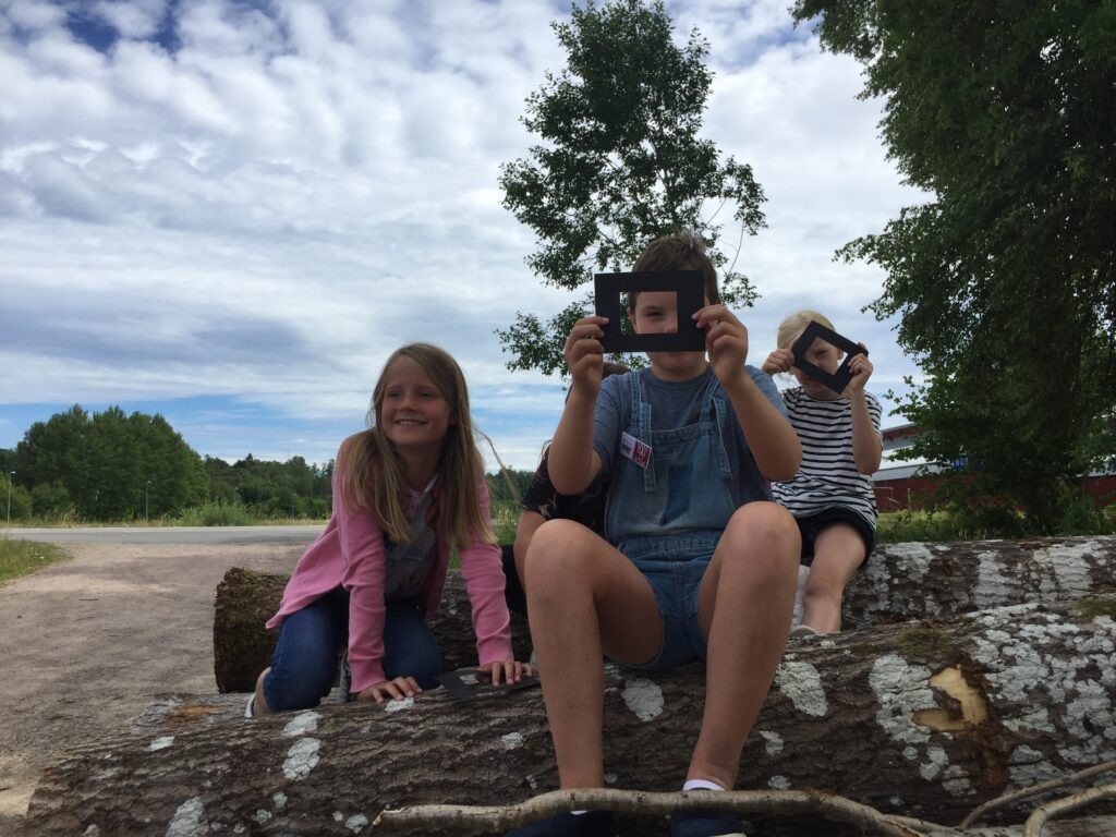Barn som håller i ramar och lär sig fotografera
